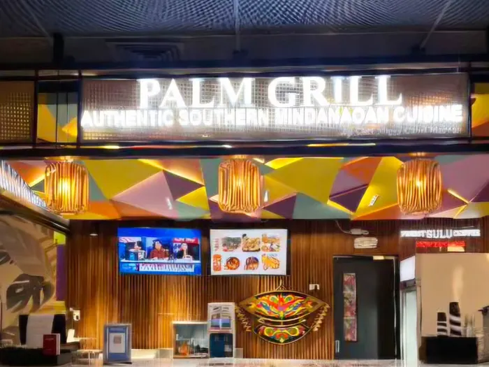 The Palm Grill counter at NAIA Terminal 3, under a lit sign and colourful geometric panels.