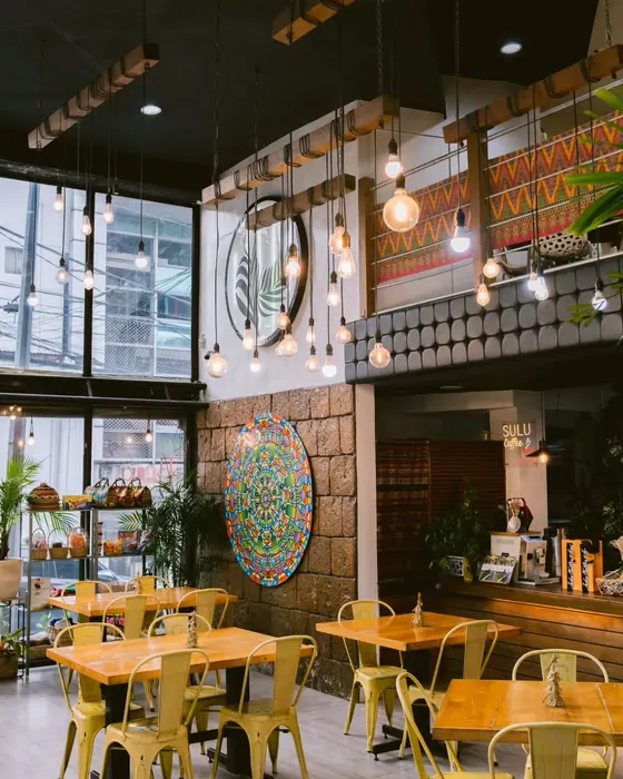 The double-height dining room at Tomas Morato, with hanging bulbs, woven wall art and framed press clippings.